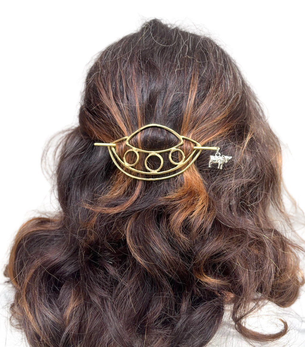a ufo hair pin with a cow being abducted hanging from the hair pin 